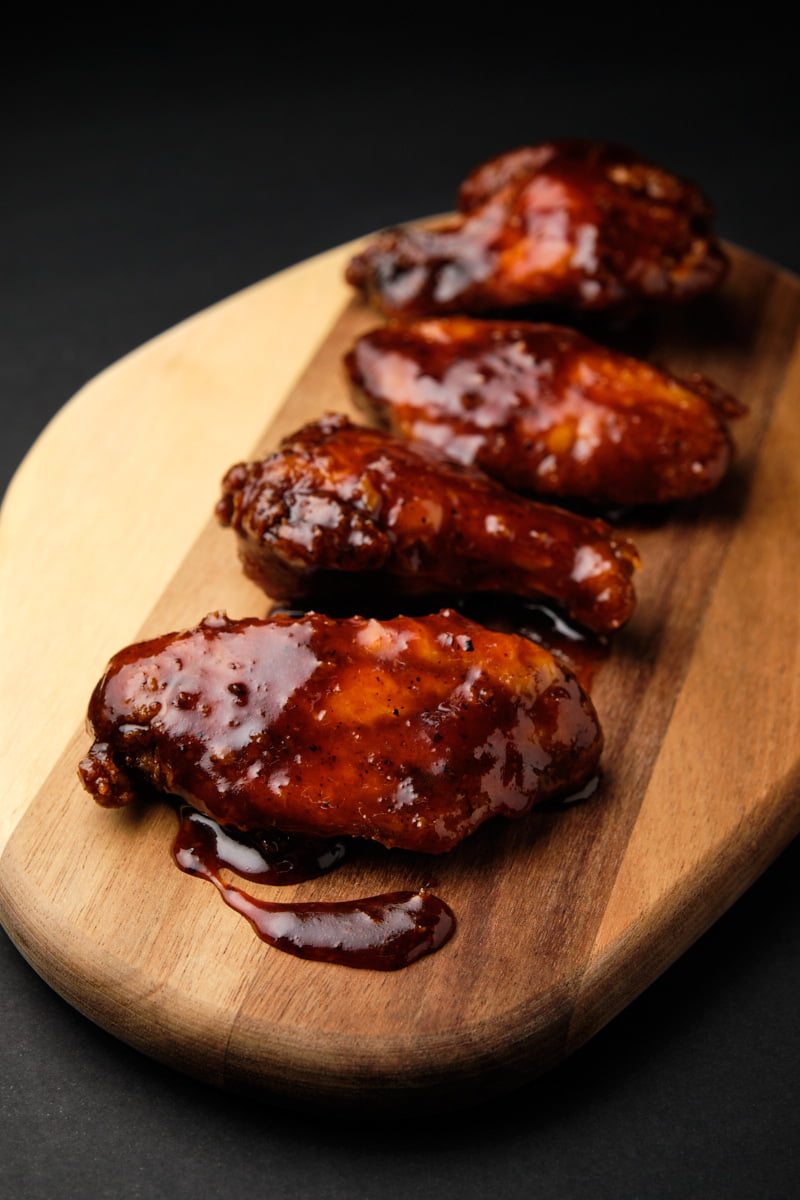 Alitas de pollo sobre tabla de madera con fondo oscuro